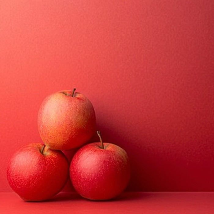 Three red apples stacked on a red background.