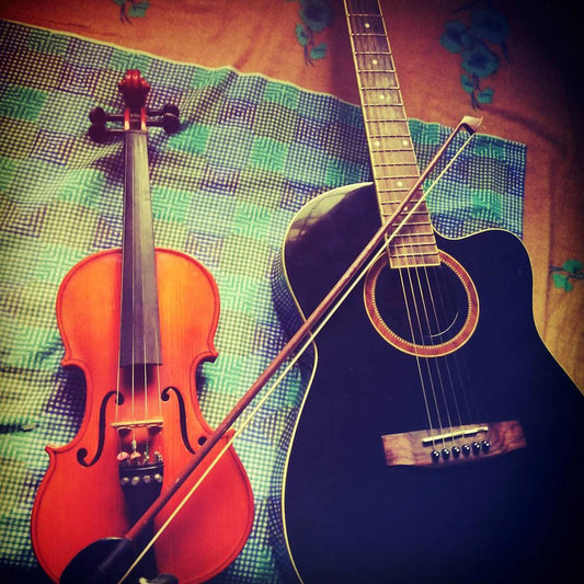 Violin and acoustic guitar on a checkered fabric background.