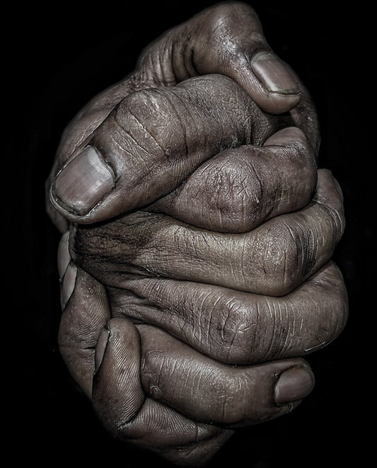 Close-up of interlocked hands with visible aging and texture on a black background.