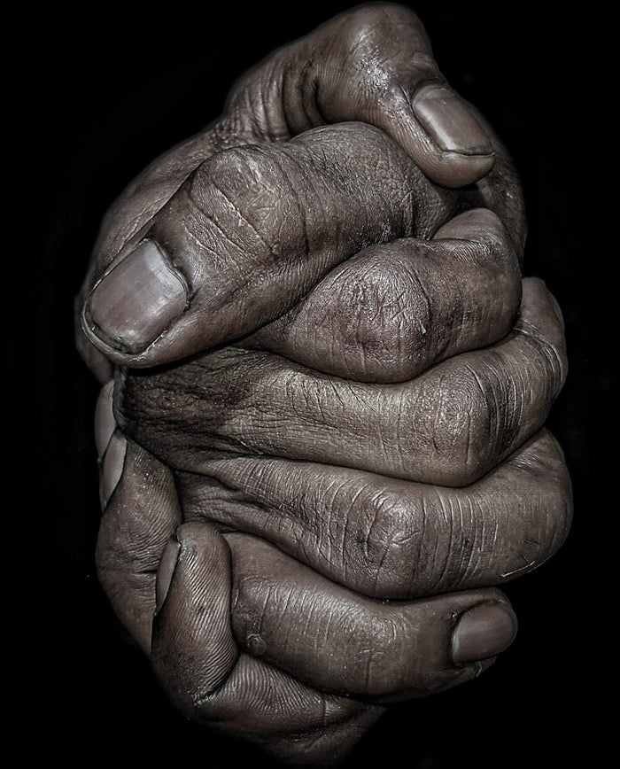 Close-up of interlocked hands with visible aging and texture on a black background.